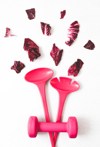 沙拉勺、一个哑铃和生菜叶放在一块轻质水泥的中央。图片下载