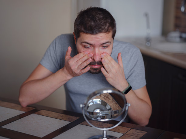 男人的美丽的概念。一个白人在检查他的皮肤。图片下载