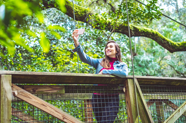 在风景优美的桥上俯瞰丛林的女子拍照，观光和异国旅行图片下载