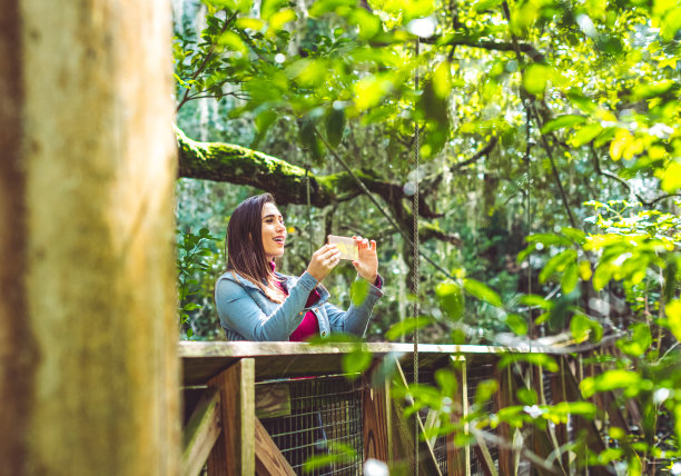 在风景优美的桥上俯瞰丛林的女子拍照，观光和异国旅行图片下载
