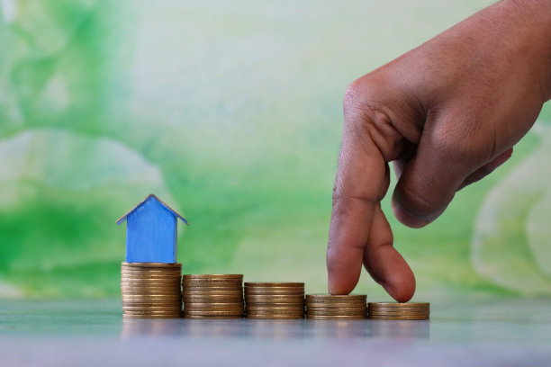 无法辨认的人的手指走上硬币楼梯走向蓝色纸板房子的图像，彩色的海滩小屋上的硬币堆栈，重点在前景，斑纹的绿色背景，家庭财务，房地产和假日储蓄概念图片下载