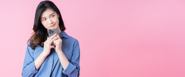 年轻的亚洲商业女性在粉红色背景下使用智能手机的图像图片下载