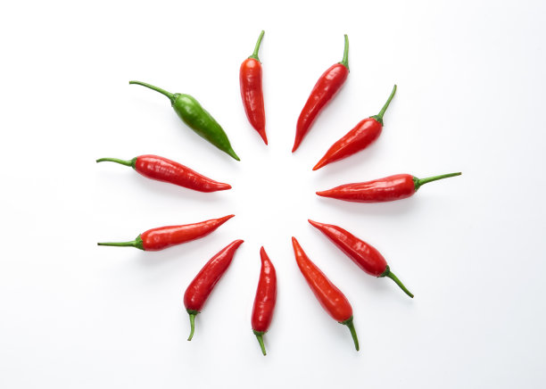 红辣椒围成一个圈，绿色的辣椒在图中突出图片下载
