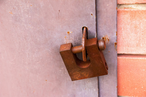 一把生锈的旧挂锁锁在金属门上。没有条目,安全。图片下载