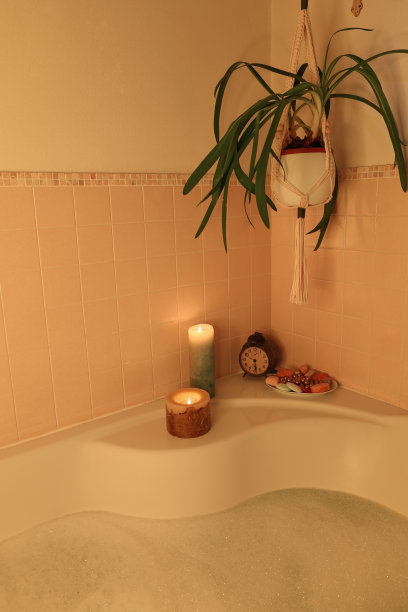 浴室角落里有蜡烛、浴缸和悬挂的植物图片下载
