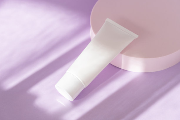 丁香裙上的护肤化妆品瓶模型。面霜，保湿霜，乳液罐塑料管的背景与自然阴影，高角度观看。图片下载