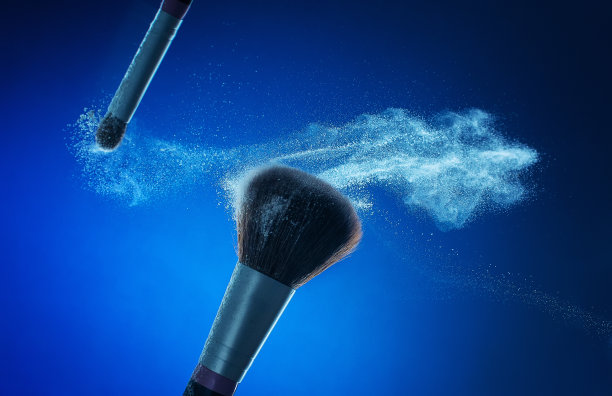 化妆刷用白色粉末在蓝色背景上爆炸。美丽的概念。图片下载