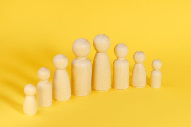 八口之家由黄色背景的木制小雕像组成。多子女家庭、多子女家庭或多成员家庭。图片下载