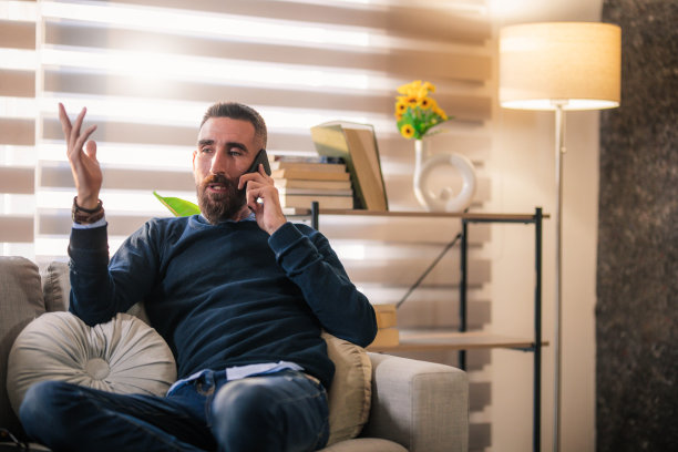 微笑的商人坐在办公室里，使用电脑和智能手机图片下载