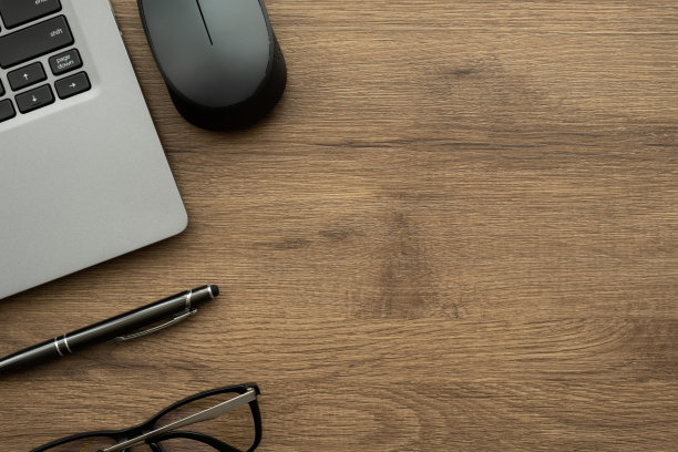 木制办公桌椅，配有笔记本电脑，黑色鼠标和笔。俯视图与复制空间，平躺。图片下载