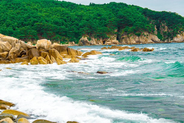 海岸线，美丽的沙滩石头和蓝色的海浪。大量的阳光。图片下载