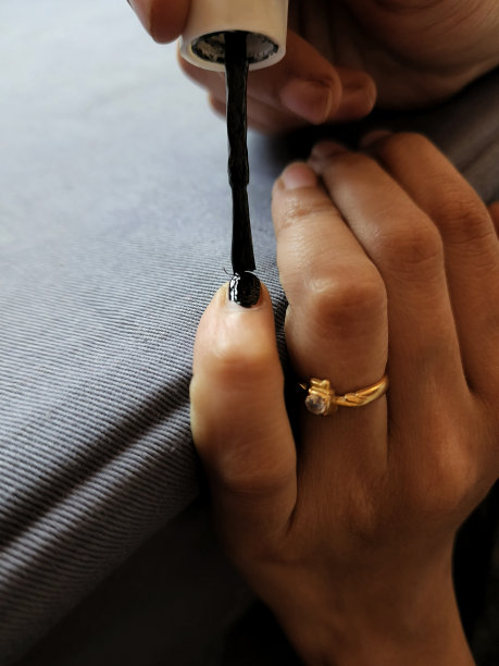 一个女孩在指甲上涂黑色指甲油或指甲油的照片。这张照片拍摄于印度卡纳塔克邦的班加罗尔，摄于自然光下。关注对象。图片下载