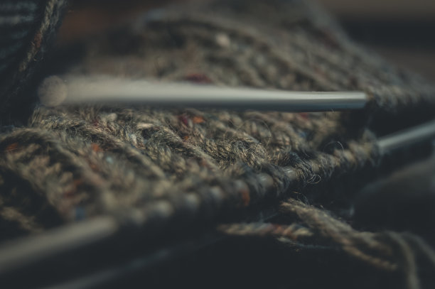 毛线袜子。羊毛制成的天然纱线。他的爱好是手工编织。选择性聚焦，黑色背景图片下载