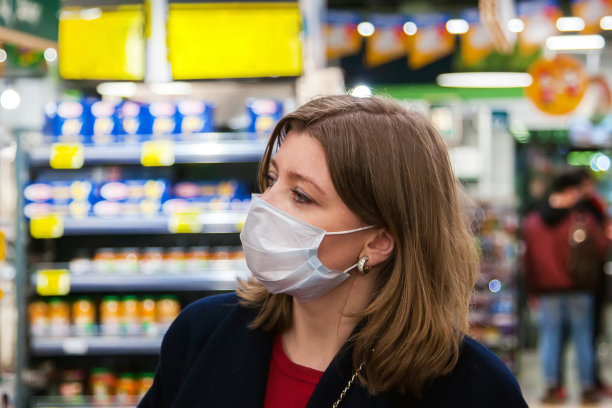 新标准的概念。在冠状病毒危机或covid - 19爆发期间，女孩在货架上挑选要买的东西。年轻女子带着一次性医用口罩购物。流行病肺炎图片下载