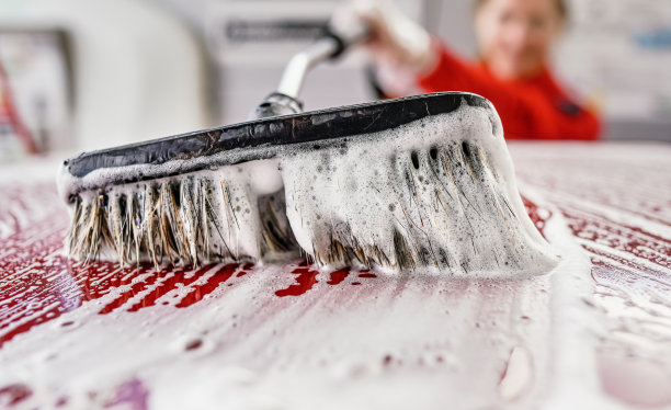 年轻女子在自助洗车场洗车。特写细节白色肥皂泡沫和刷移动屋顶图片下载