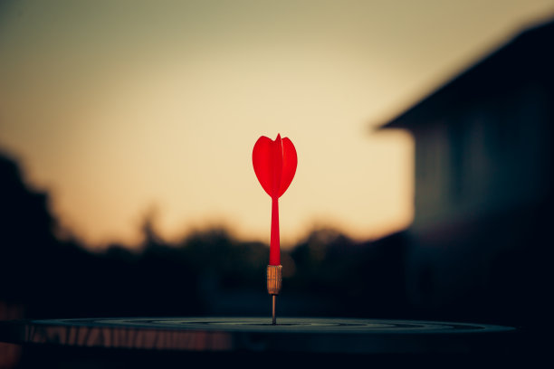 近距离射击红色飞镖箭在镖靶中心在深蓝色的天空背景。事业目标或成功目标与赢者观念。图片下载