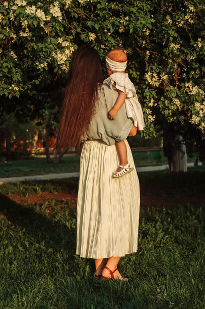 母亲和小女儿在一棵盛开的苹果树旁。图片下载