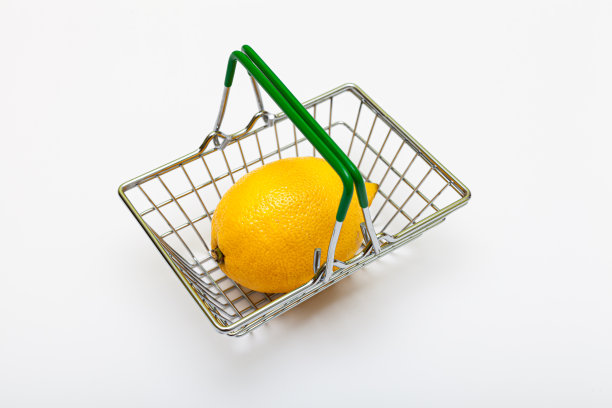 一个成熟的黄色柠檬躺在一个小杂货篮子旁边图片下载