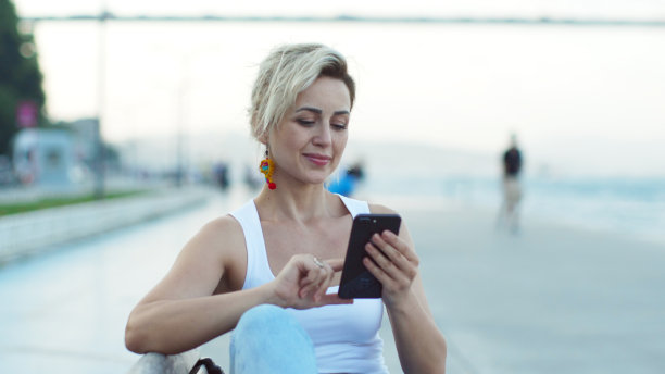 在公园里用智能手机写信息的女人。图片下载