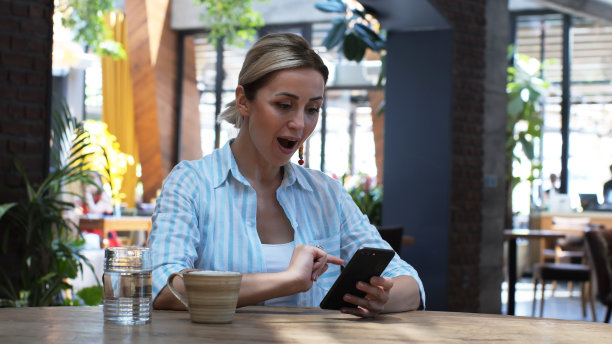 年轻可爱的女人使用手机的特写，拿着智能手机，坐在咖啡馆里回复短信的照片，电话，信件，instagram，室内肖像，帖子。图片下载
