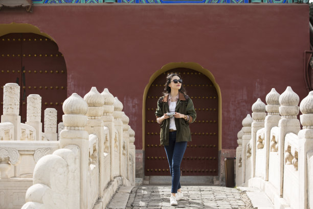 年轻的女摄影师走在古代拱桥的股票照片图片下载