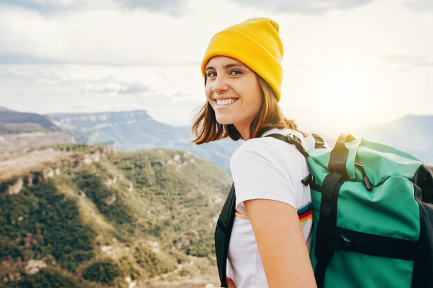 背景年轻快乐微笑的女人背包客在山顶落基山脉图片下载