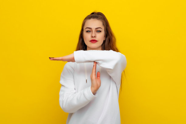 不满的年轻女孩的肖像表现出暂停的姿势，需要停下来，在努力学习后要求休息，表情严肃地看着镜头，穿着白色休闲风格的运动衫图片下载