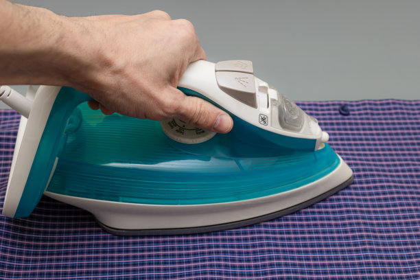 一只手拿着熨斗，用来熨笼子里的衬衫图片下载