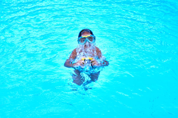 小女孩泡在游泳池里玩。图片下载