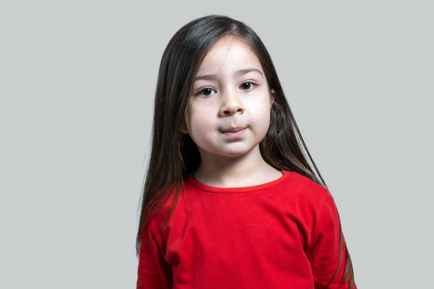 一个微笑的女孩的肖像看着镜头与愉快的面部表情在灰色的背景图片下载