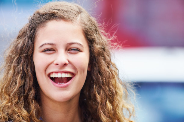 美丽的卷发年轻女子在户外快乐地笑着图片下载