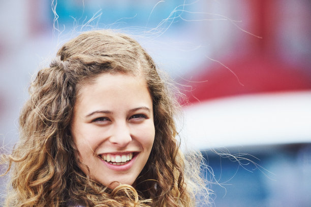 美丽的卷发年轻女子在户外快乐地笑着图片下载