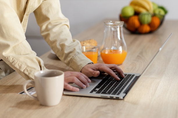 一个商人在家里吃早餐时用笔记本电脑工作的特写图片下载