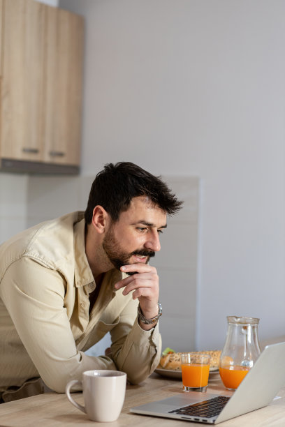 漂亮的大胡子男人在家里用笔记本电脑工作图片下载