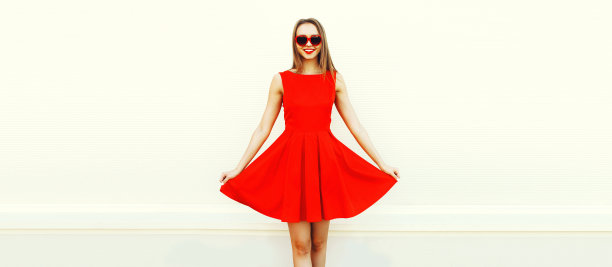 漂亮的年轻女子穿着红色的连衣裙，白色背景上的心形太阳镜，空白的广告文字拷贝空间图片下载