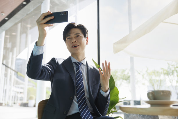 亚洲商人在咖啡店使用移动视频电话图片下载