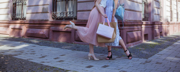 两个穿着裙子和高鞋的女孩拿着购物袋图片下载