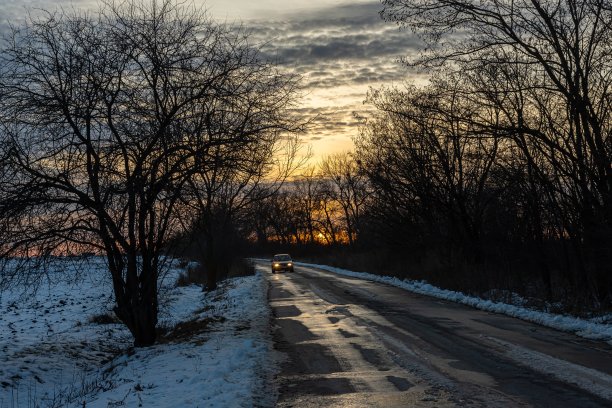 冬天的道路，阳光明媚的夕阳。运动的方向。车路线。阳光灿烂的日落。早上的日出。白色的雪。暮光。图片下载