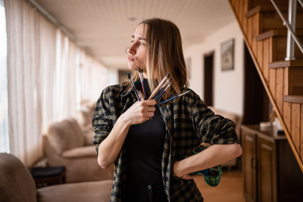 一名年轻的白人女性艺术家，专业或业余画家学生站在家里，手里拿着调色板和画笔摆姿势，复制空间腰部以上图片下载