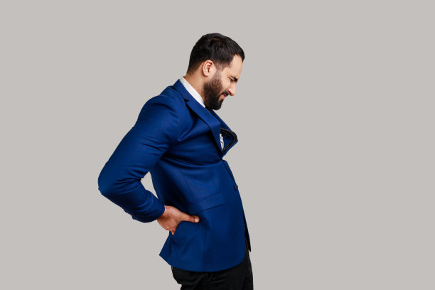 侧视图，大胡子男子站着，闭着眼睛，忍受着腰痛，肾脏发炎。图片下载