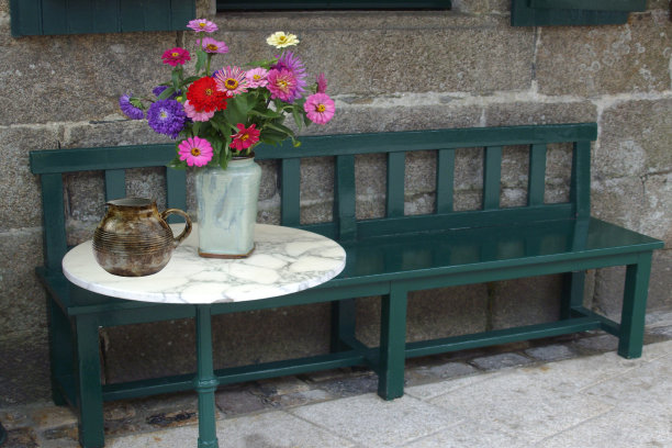 有靠背Café露台的公共木凳前有一张镶着鲜花的圆形咖啡桌图片下载