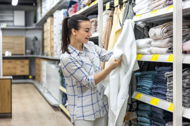 一位年轻妇女在一家家居用品店挑选了一条蓝色的浴巾。图片下载