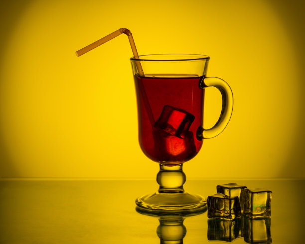 冰镇的茶，鸡尾酒，水果饮料在一个高的玻璃杯和一根吸管在桌子上与冰块。图片下载