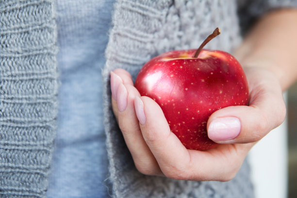 红色成熟多汁的苹果在女性手中。图片下载