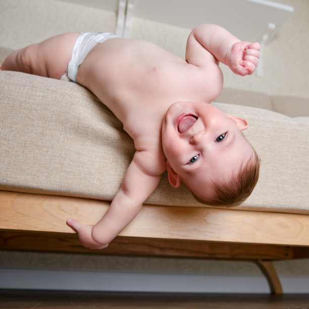 婴儿婴儿从家里客厅的沙发上掉下来。蹒跚学步的孩子从床上爬起来。没有父母监督的儿童的安全问题图片下载