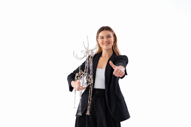 年轻的女商人手持灯饰圣诞鹿装饰穿着黑色西装孤立在白色背景图片下载