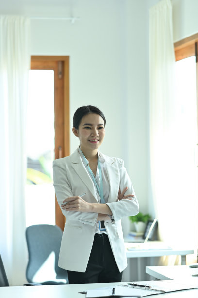 一名年轻的办公室女性交叉双臂站在现代工作空间作为背景。图片下载