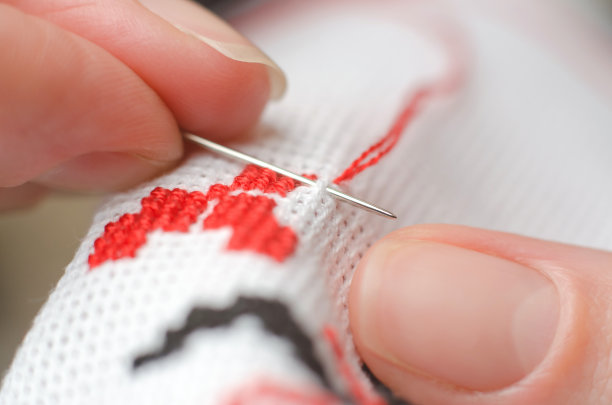 特写的女性手十字绣在白色帆布上。一名妇女用十字绣乌克兰的国家象征图片下载