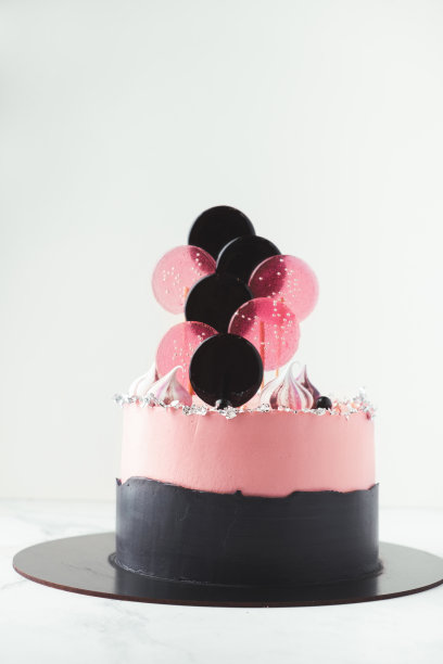 生日蛋糕，上面有粉色奶油芝士糖霜和棒棒糖。图片下载