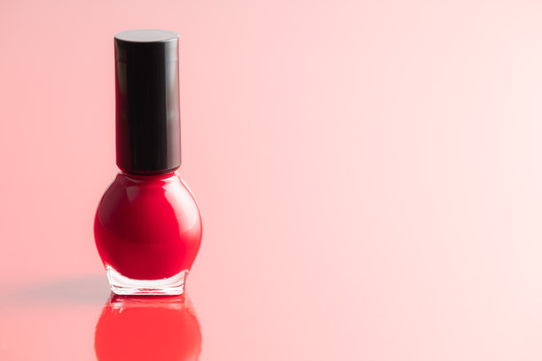 红色背景上的彩色指甲油瓶子。图片下载